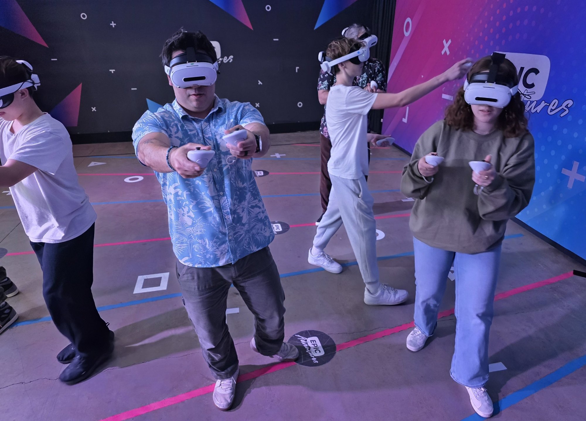 Six players in VR headsets playing free-roam virtual reality together at Epic Adventures arena