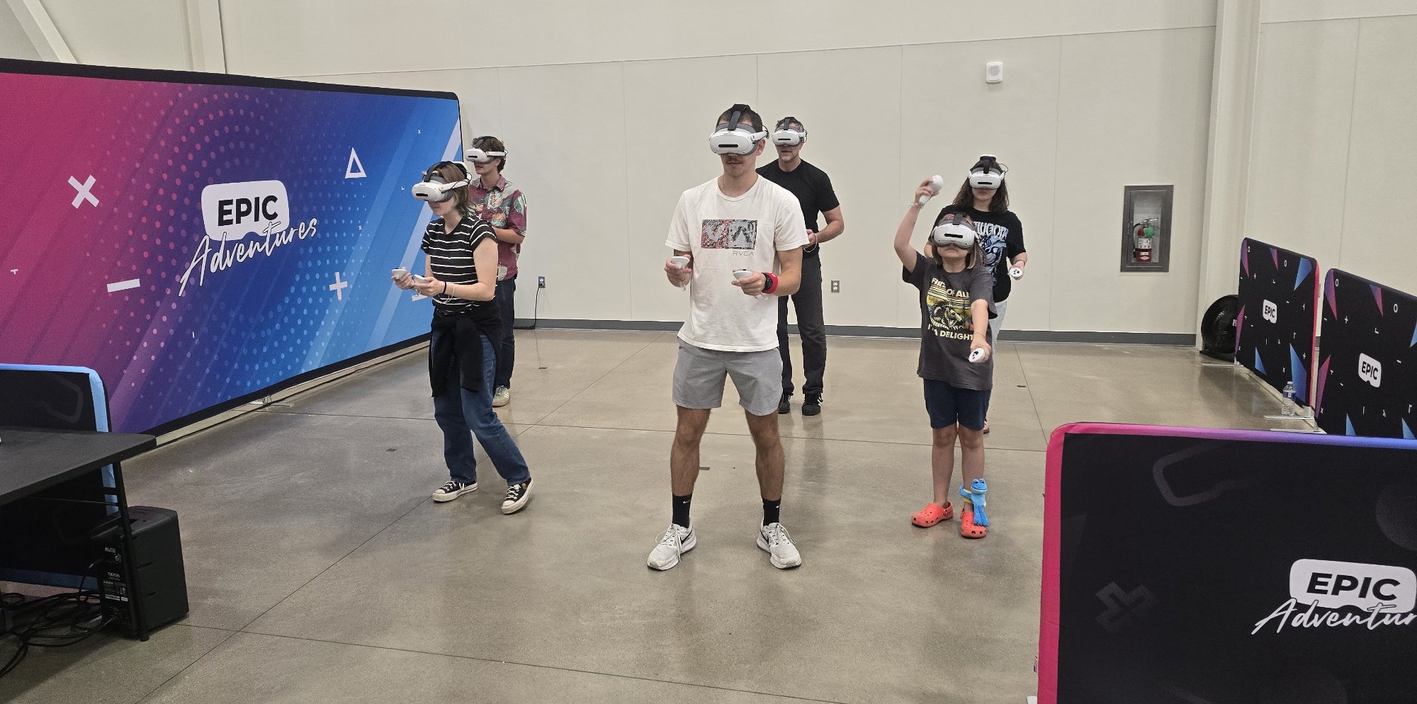 Five players in VR headsets playing free-roam virtual reality at a mobile Epic Adventures arena set up at a convention center