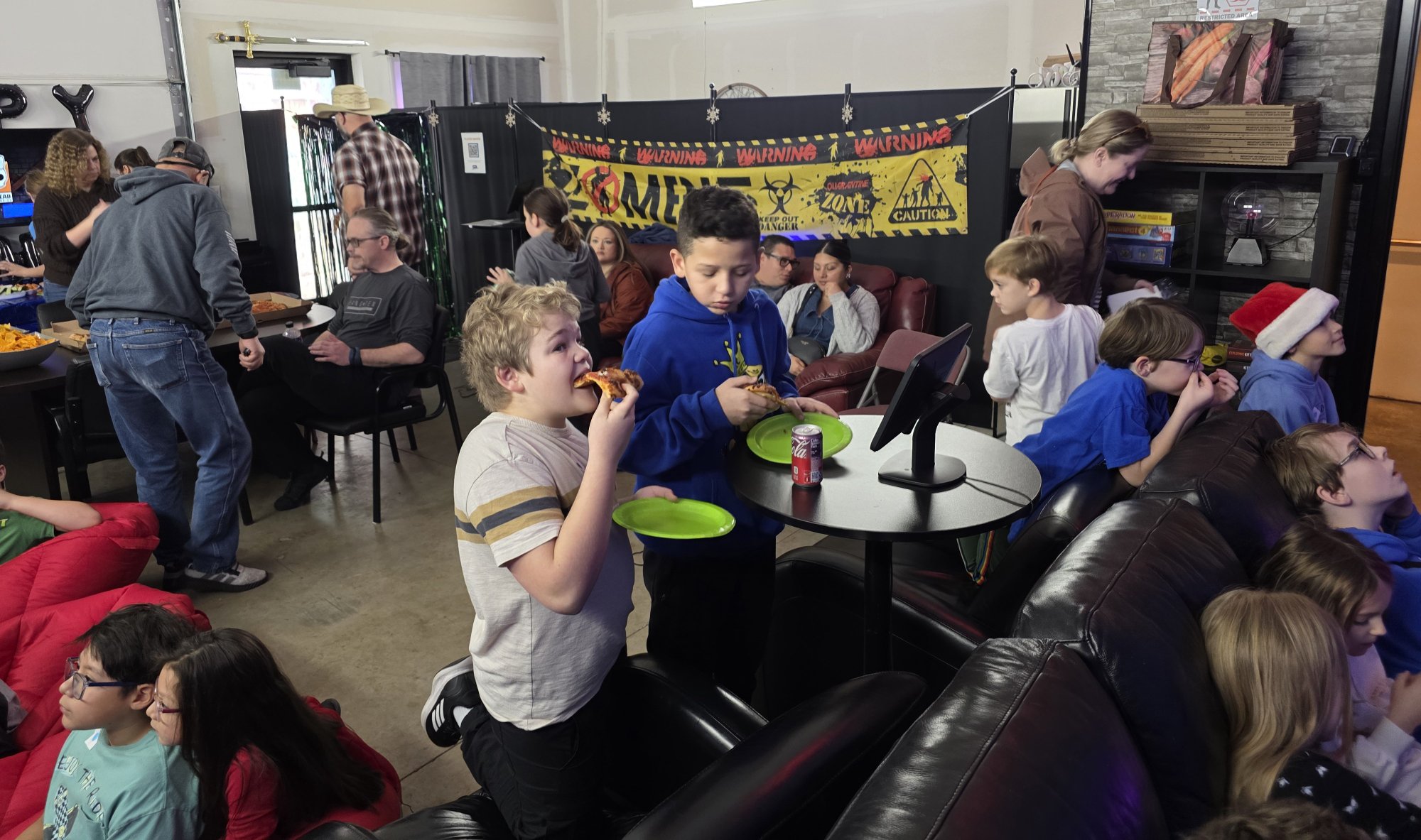 Kids eating pizza at a VR birthday party at Epic Adventures in Vancouver WA with parents and friends watching VR action