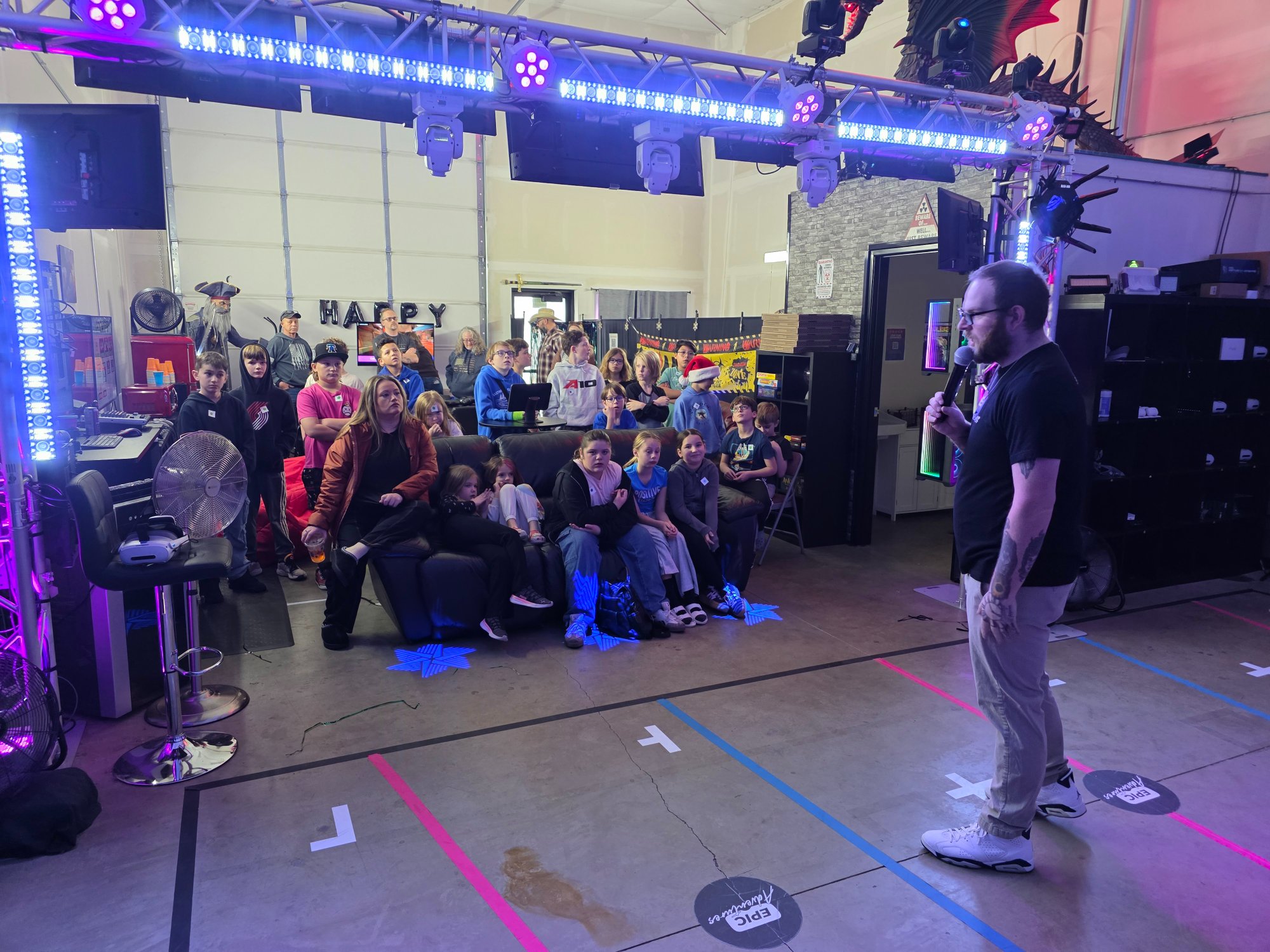 Game host addressing a packed birthday party crowd of kids and parents at Epic Adventures VR in Vancouver WA